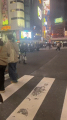 Pedestrians cross busy Shibuya crosswalk amid digital billboards