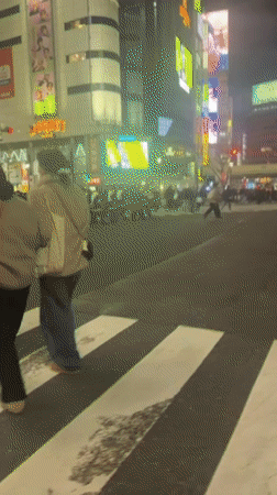 Pedestrians cross busy Shibuya crosswalk amid digital billboards