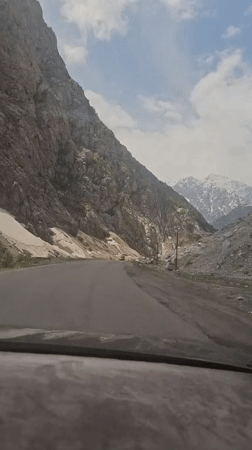 Vehicle travels through snowy mountain pass in Tajikistan