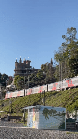 Train passes castle tower in Sochi amid clear skies