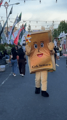 Book mascot walks street waving in Klungkung Indonesia