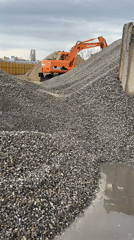 Excavator positioned on gravel pile at construction site