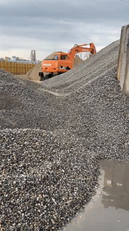 Excavator positioned on gravel pile at construction site