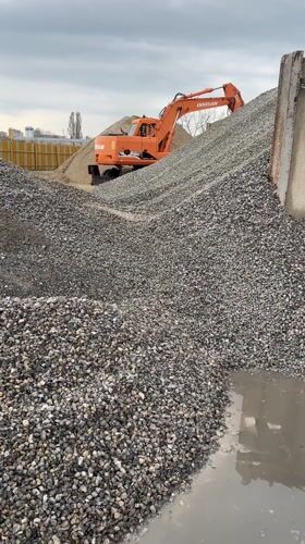Excavator positioned on gravel pile at construction site