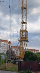 Yellow construction crane looms over a lot with parked vehicles