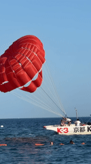 Red parasail over Budva's Adriatic coast on a sunny afternoon