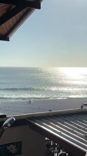 Morning surf session observed from beachfront bar in Kuta