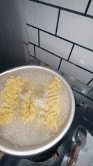 Woman cooks Indomie noodles in Gelam kitchen during evening