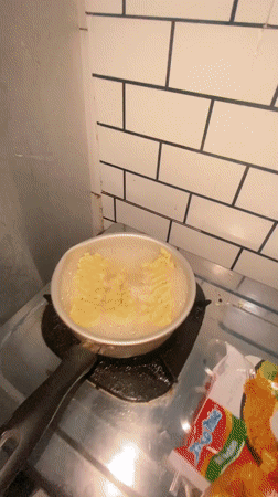 Woman cooks Indomie noodles in Gelam kitchen during evening