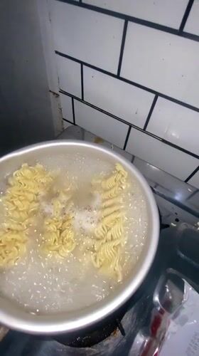 Woman cooks Indomie noodles in Gelam kitchen during evening