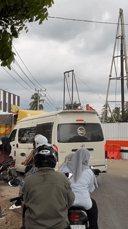 Motorcyclists wait in traffic behind van in Indonesian street