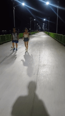 Child walks illuminated bridge near pyramid structure in Thailand