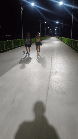 Child walks illuminated bridge near pyramid structure in Thailand
