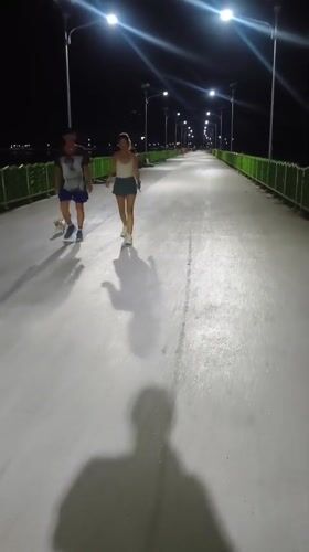 Child walks illuminated bridge near pyramid structure in Thailand