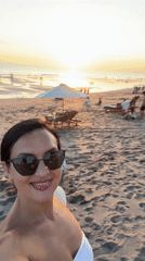 Woman takes selfies on crowded North Kuta beach at sunset