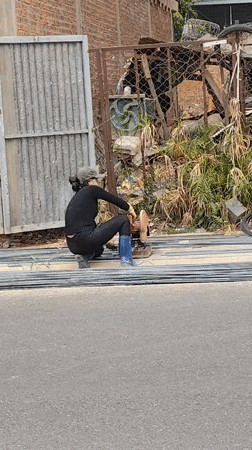 Woman cuts metal bars on street in Da Lat