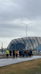 Morning joggers gather near Kazan Arena on cloudy day