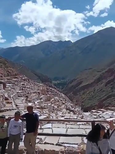 Tourists visit historic Maras Salt Mines under sunny skies