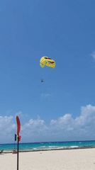Parasailing with cartoon-faced parachute captured at Playa del Carmen
