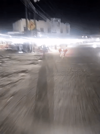 Motorcycle travels lit commercial street in Keudegeudong evening