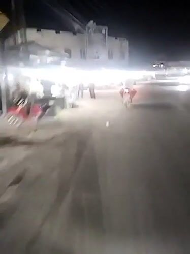 Motorcycle travels lit commercial street in Keudegeudong evening