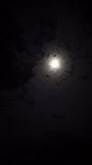 Full moon visible through drifting clouds over Langsa, Indonesia