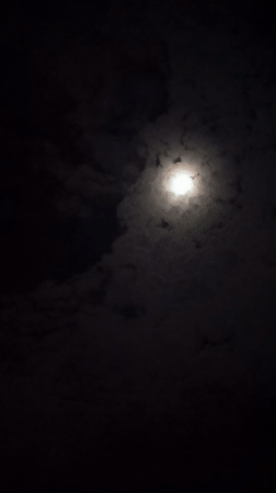 Full moon visible through drifting clouds over Langsa, Indonesia