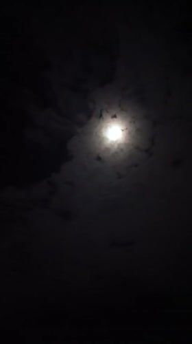 Full moon visible through drifting clouds over Langsa, Indonesia