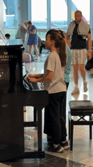 Two girls play piano together in Budapest airport terminal