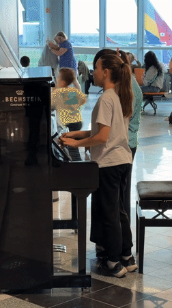 Two girls play piano together in Budapest airport terminal