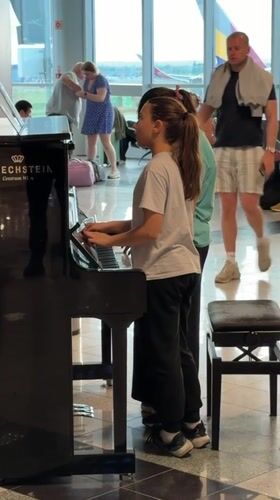 Two girls play piano together in Budapest airport terminal