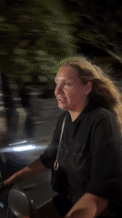 Woman rides scooter through North Kuta streets at night