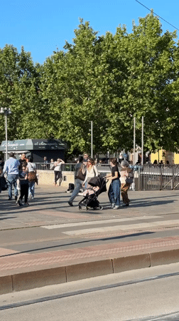 Busy Milan square captures street performers, fairground, pedestrians on sunny afternoon