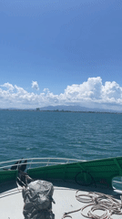 Boat passenger films calm waters, distant cityscape near Vietnam coast