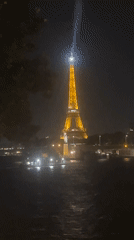 Eiffel Tower glowing at night, seen from the Seine