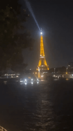 Eiffel Tower glowing at night, seen from the Seine