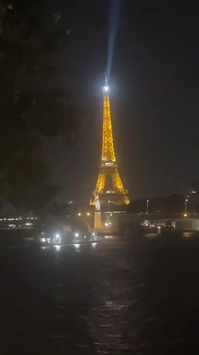 Eiffel Tower glowing at night, seen from the Seine