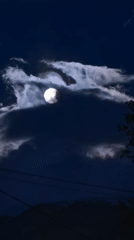 Full moon drifts through clouds over Bulgarian village