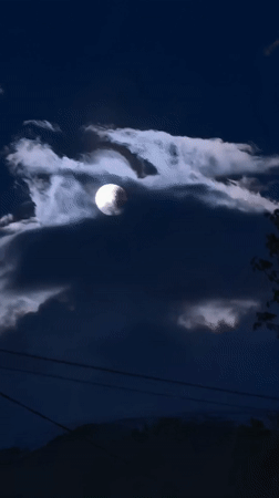 Full moon drifts through clouds over Bulgarian village