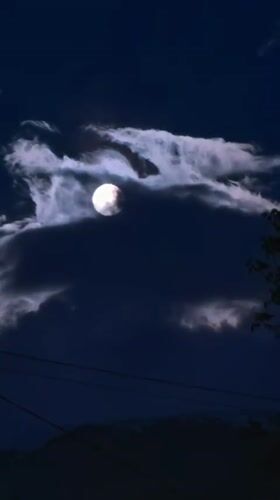 Full moon drifts through clouds over Bulgarian village