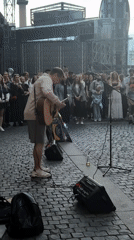 Acoustic street performance in a cobblestone plaza draws a crowd