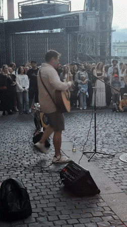 Acoustic street performance in a cobblestone plaza draws a crowd