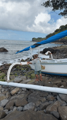 Man tends to beached outrigger boat on Indonesian shore
