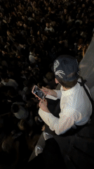 Person with skull cap watches crowd from ledge in Buenos Aires