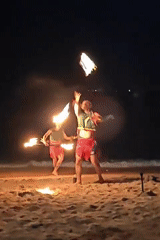 Fire dancers perform on a Pattaya beach at night