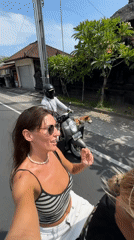 Women take selfie while riding scooter in North Kuta