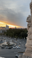 Tourist welcomes friend to Madrid with greeting card at sunset