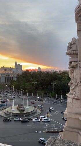 Tourist welcomes friend to Madrid with greeting card at sunset