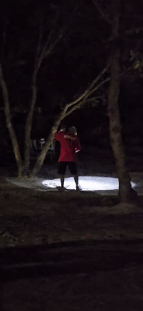 Night cleaning: Person sweeps outdoor area with headlamp in Denpasar