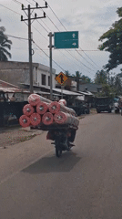 Motorcycle transports carpet rolls through Indonesian towns early morning